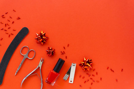 Christmas flat lay of manicure accessories and nail polish with holiday decorations on a red background. Space for text.の写真素材