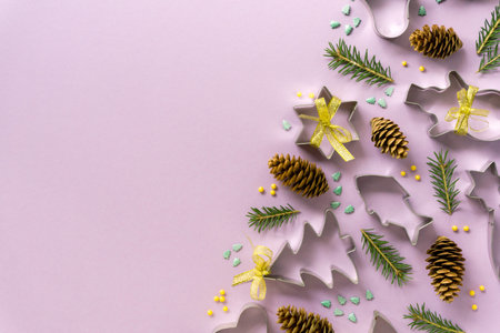 Festive flat lay of christmas cookie cutters with sweet sprinkles on a lilac background. Space for...