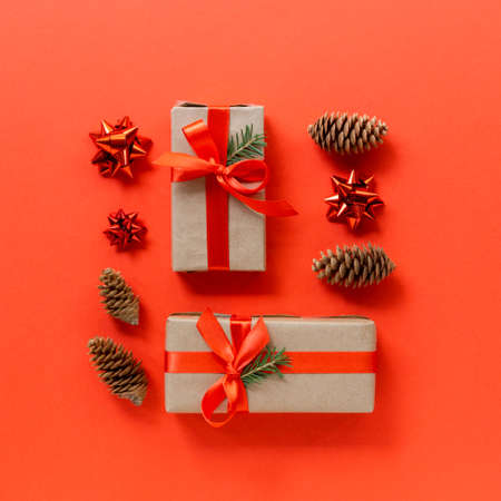 Holiday gift boxes with ribbon, fir and cones on a red background. Flat lay for christmas and new yearの写真素材