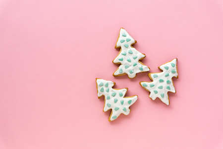 Homemade christmas gingerbread cookies in the shape of trees on a pink background, space for textの写真素材