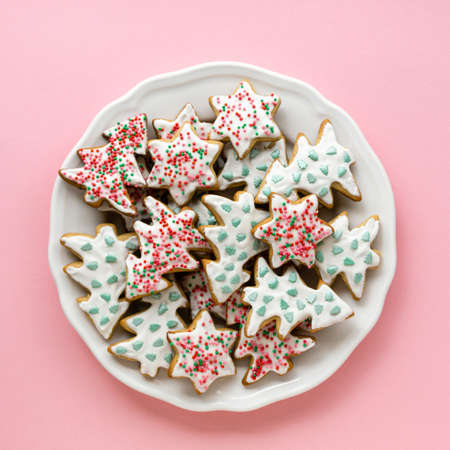 Homemade christmas gingerbread cookies in the shape of stars and trees on a white plate, top viewの写真素材
