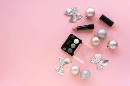 Christmas or new year flat lay of makeup products and decorations. Eyeshadow palette and lipstick on a pink backgroundの写真素材