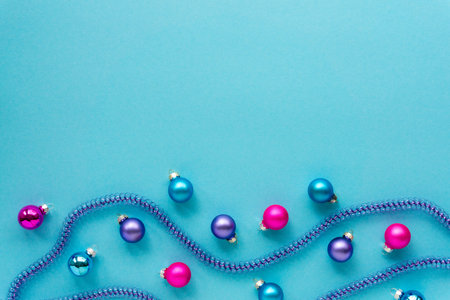 Christmas or new year composition with multicolored balls and tinsel on a blue background. Space for...
