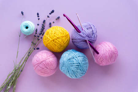 Flat lay of colored yarn balls for crocheting with lavender on a lilac background, top view.の写真素材