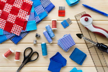 Items for patchwork. Pieces of fabric and sewing accessories on a wooden background.