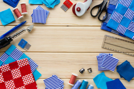 Items for patchwork. Pieces of fabric and sewing accessories on a wooden background. Space for text.