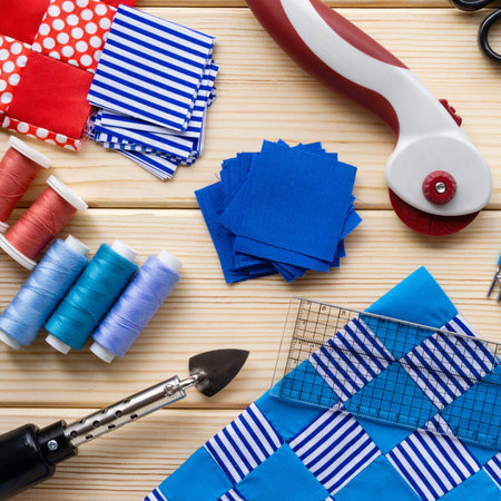 Items for patchwork. Pieces of fabric and sewing accessories on a wooden background.