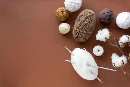 Knitting threads. Balls of beige and white yarn on a brown background, space for text.の写真素材