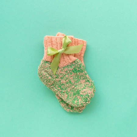 Pair of knitted baby socks for girl on mint background, top view.の写真素材