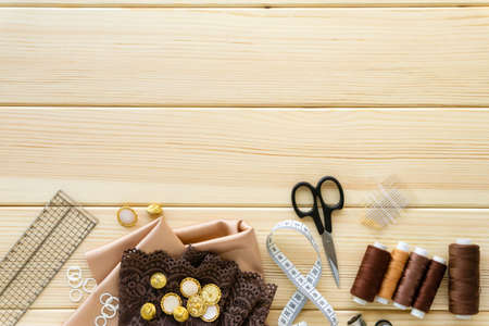 Flat lay of sewing accessories. Cloth, threads and tailoring tools on wooden background, space for text.の写真素材