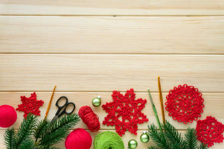 Christmas flat lay of items for needlework. Knitted snowflakes, threads and hooks on wooden background, copyspace.の写真素材