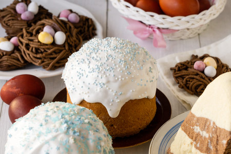 Traditional easter food. Cakes, nest cookies and colored eggs on wooden table