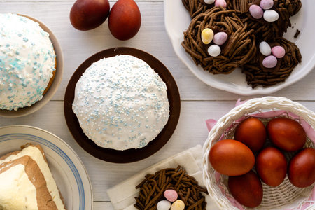 Traditional easter food. Cakes, nest cookies and colored eggs on wooden table