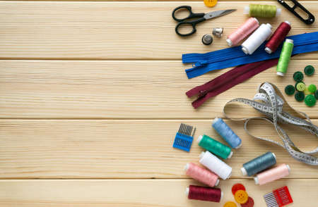 Flat lay of accessories for tailor. Set of sewing supplies on wooden background, space for text.の写真素材
