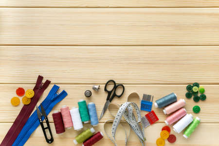 Flat lay of accessories for tailor. Set of sewing supplies on wooden background, space for text.の写真素材