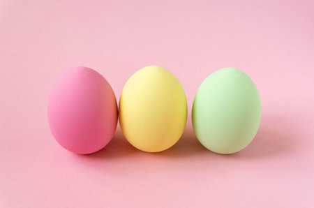 Three multicolored easter painted eggs on pink backgroundの写真素材