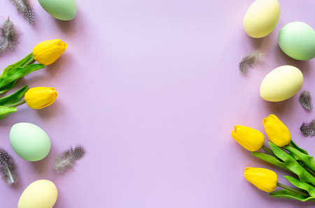 Easter flat lay. Painted eggs with tulips and feathers on lilac background, space for textの写真素材