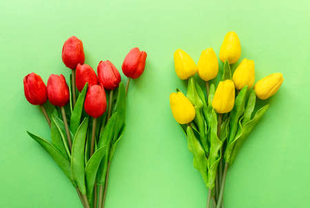 Two bouquets of red and yellow tulips on green background, top viewの写真素材