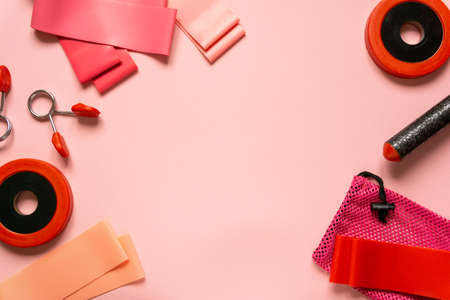 Flat lay of sports equipment. Fitness rubber bands and dumbbells on pink background, space for textの写真素材