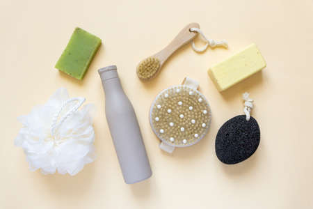 Flat lay of bath products and items. Shampoo, soap, massage brushes and washcloth on beige background, top viewの写真素材