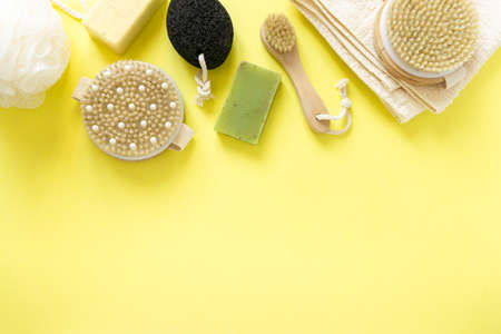 Products and items for bathroom. Massage brushes, soap, pumice stone and towel on yellow background, copyspaceの写真素材