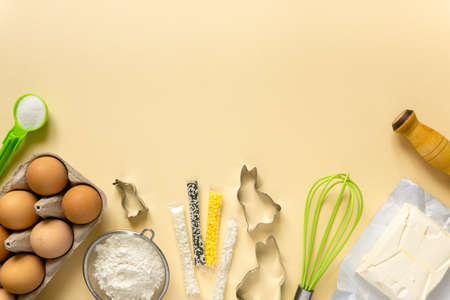 Easter baking flat lay. Cookies ingredients and kitchenware on beige background, space for textの写真素材