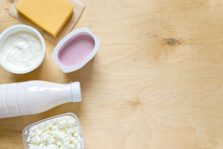 Flat lay of dairy products. Milk, curd, sour cream, cheese and yogurt on wooden background, copyspaceの写真素材