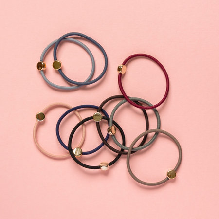 Set of multicolored hair ties on pink background, top view