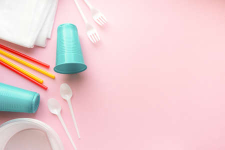Flat lay of various disposable plastic tableware on pink background, space for textの写真素材