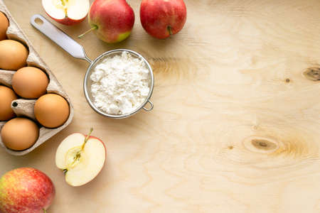 Ingredients for baking pie. Eggs, flour and apples on wooden background, copyspaceの写真素材