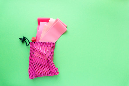 Set of fitness rubber bands in bag on green background, space for textの写真素材