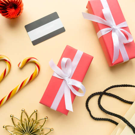 Christmas shopping concept. Gift boxes, lollipops cane and credit card on beige background, top viewの写真素材