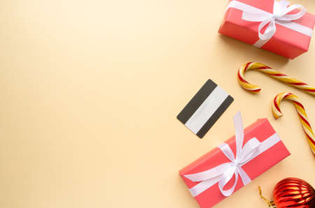 Christmas shopping concept. Gift boxes, lollipops cane and credit card on beige background, copyspaceの写真素材