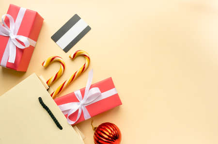 Christmas shopping concept. Gift boxes, lollipops cane and credit card on beige background, copyspaceの写真素材