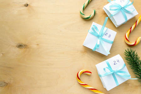 Christmas advent calendar flat lay. Homemade gift boxes with blue ribbon on wooden background, space for textの写真素材