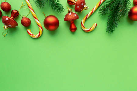 Christmas flat lay. Holiday decorations, lollipops cane and fir branches on green background, space for textの写真素材