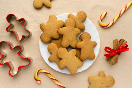 Homemade christmas gingerbread cookies in the shape of man on beige textile background, top viewの写真素材