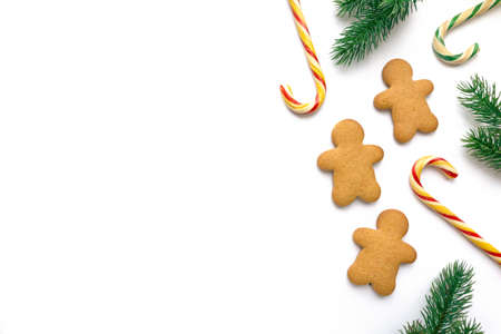 Christmas gingerbread cookies in the shape of man with lollipops and fir branches on white background, space for textの写真素材