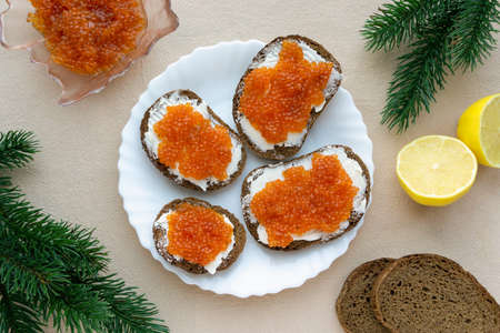 Sandwiches with butter and red caviar on beige textile background, top viewの写真素材