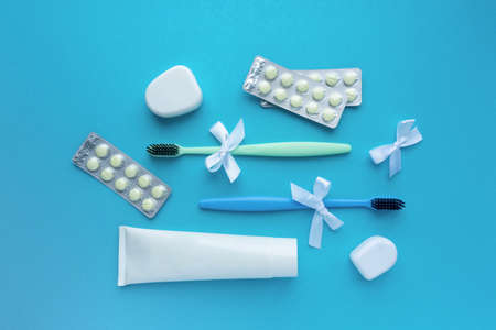 Flat lay for dentist day. Toothbrushes, paste, dental floss and pills on blue background, top viewの写真素材