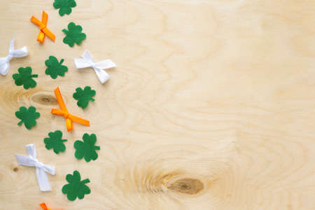 Flat lay for saint Patricks day. Paper clover leaves with bows on wooden backgroundの写真素材