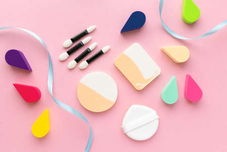 Makeup flat lay. Various foundation sponges and eyeshadow applicators on pink backgroundの写真素材