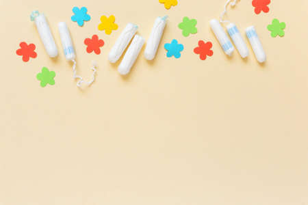 Female menstrual tampons with paper flowers on beige background, space for textの写真素材