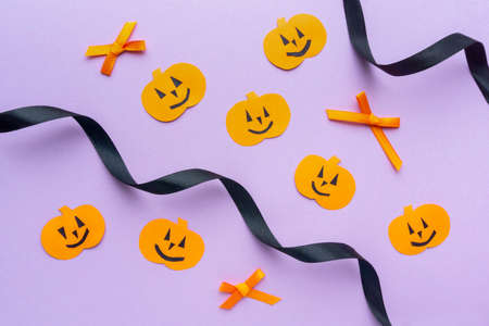Halloween flat lay. Paper pumpkins with black ribbon on lilac background, top viewの写真素材