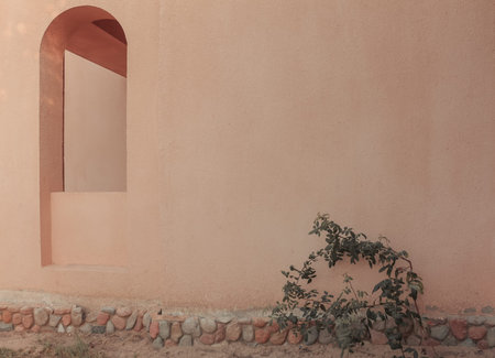 An arch window in the wall of the arabic building. Light summer shadows on the wall.