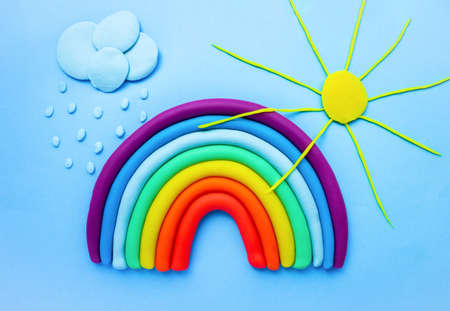 Colorful rainbow, sun and clouds of plasticine on blue background. Sky and the sun. Made from plasticの写真素材