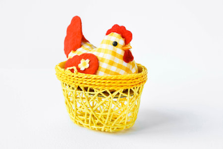 Decorative chicken in a yellow wicker basket on a white isolated background with space for text. Easter card Provence. Easter composition.の写真素材