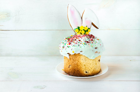 Easter cake stands on a white plate on a white wooden background. Traditional Christian Easter...