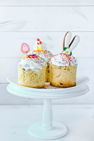 Three Easter cakes stand on a white plate on a white wooden background. Traditional Christian Easter...