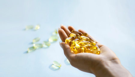 Close-up medicine yellow transparent pills, omega 3 fish oil capsules, vitamin D. Many yellow transparent capsules in hand close-up. The concept of health, vitamins, and medicine.の写真素材